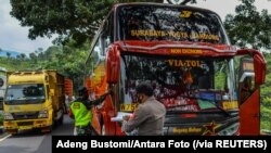 Para petugas memeriksa sebuah bus penumpang pada hari pertama penerapan larangan mudik nasional untuk mencegah penyebaran pandemi COVID-19, di Tasikmalaya, Jawa Barat, 6 Mei 2021. (Foto: Adeng Bustomi/ Antara Foto via Reuters)