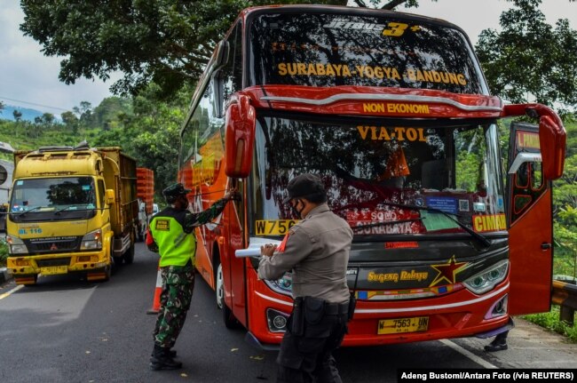 Para petugas memeriksa sebuah bus penumpang pada hari pertama penerapan larangan mudik nasional untuk mencegah penyebaran pandemi COVID-19, di Tasikmalaya, Jawa Barat, 6 Mei 2021. (Foto: Adeng Bustomi/ Antara Foto via Reuters)