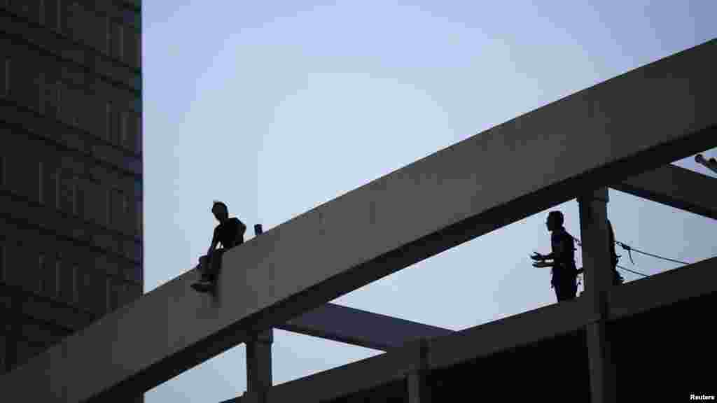 A pro-government supporter, left, threatens to jump off a pedestrian bridge unless roadblocks set up by Hong Kong pro-democracy protesters are removed in front of the government headquarters in Hong Kong, Oct. 5, 2014. 