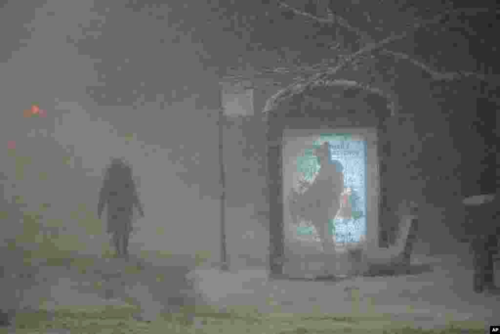 A woman walks to a bus stop on Martin Luther King Jr. Drive during the pre-dawn hours in Chicago. A major winter storm brought a mix of rain, freezing rain and snow to the middle section of the United States as airlines canceled hundreds of flights.