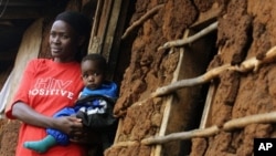 A Kenyan AIDS victim holds her child outside her mud shack in Kibera, Kenya's largest slum, 19 Jul 2005 (file photo)