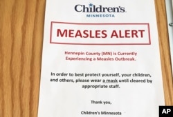 In this May 2, 2017 photo, a sign at the specialty clinic at Children's Minnesota in Minneapolis, alerts patients to a measles outbreak in the area.