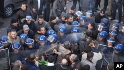 Demonstrators, foreground, asking for political change in their country, face riot policemen, in Algiers, Algeria, 22 Jan 2011