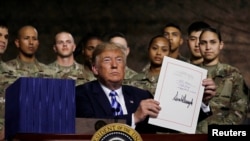 川普總統在紐約州德拉姆堡美國陸軍第10山地師的軍人面前舉起他剛剛簽署的《2019年國防授權法》。（2018年8月13日）