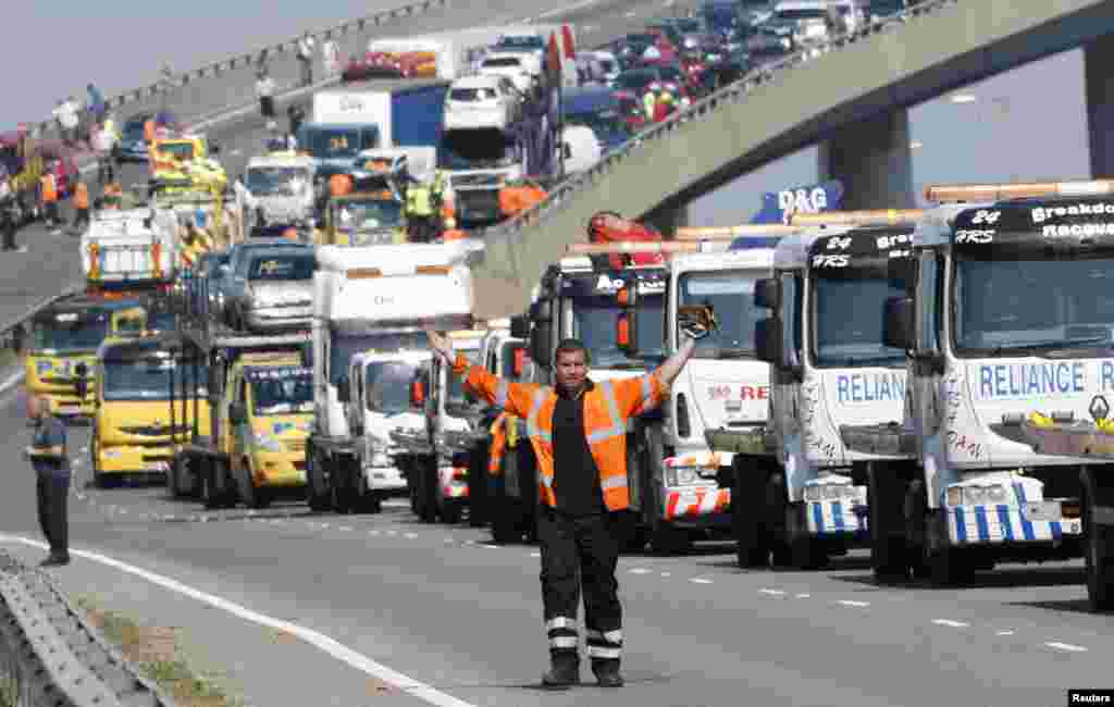 A rescue worker gestures in front of recovery trucks lined up to collect over 100 vehicles involved in multiple collisions, which took place in dense fog during the morning rush hour, on the Sheppey Bridge in Kent, east of London. Eight people were seriously injured and dozens hurt in the multiple crashes.