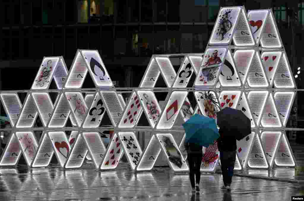 People look at an illuminated light installation called &quot;House of Cards&quot; during a technical check for the Festival of Lights in Berlin. Several landmarks of the German capital, including boulevards, squares, towers, historical and modern buildings, will be illuminated during the festival.