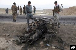 FILE - Afghan security forces gather at the site of Monday's suicide attack near the Bagram Air Base, north of Kabul, Afghanistan, April 9, 2019.