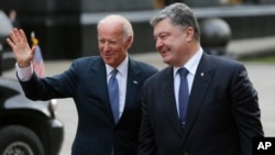 ປ. ຢູ​ເຄຣນ ທ່ານ Petro Poroshenko, ຂວາ, ຍິ້ມ ກັບ​ຮອງ ​ປ. ສະຫະລັດ ທ່ານ Joe Biden ຍົກມືໃຫ້ບັນດານັກຂ່າວ ທີ່ນະຄອນ Kyiv, ຢູເຄຣນ, 7 ທັນວາ, 2015. 