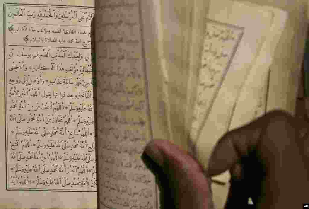 这张2004年3月16日拍摄的照片显示一名少年在马里廷巴克图一所土坯房子里一边翻阅一部古旧的伊斯兰手稿一边吟诵。