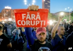 FILE - A man holds a poster that reads "Without Corruption" during a protest in Bucharest, Romania, May 3, 2017.