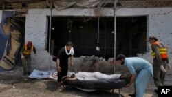 Pakistani volunteers and rescue workers remove a lifeless body from the site after a bomb explosion in Peshawar, Pakistan, May 11, 2014. 