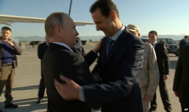 FILE - In this Dec. 11, 2017, frame grab made available by Russian Presidential TV Syrian President Bashar al-Assad, right, greets Russian President Vladimir Putin upon his arrival to the Hemeimeem air base in Syria.