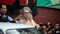 FILE - Bangladesh's former Prime Minister Khaleda Zia holds a black flag as she stands at her office in Dhaka, Jan. 5, 2015. A court issued an arrest warrant for Zia on March 30, 2016, over the 2015 fire-bombing of a bus that killed two people and injured many others.