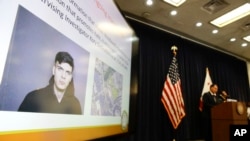 The image of Samuel Woodward is displayed as Orange County District Attorney Tony Rackauckas, right, speaks during a news conference, Aug. 2, 2018, in Santa Ana, Calif. Rackauckas said officials would file a hate crime sentencing enhancement against Woodward, 21, in the slaying of Blaze Bernstein, 19. 