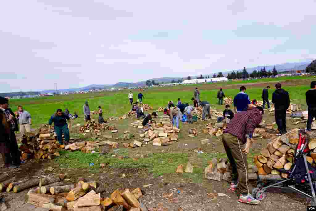 Migrants sort and stack the wood delivered to the camp for fires, March 9, 2016. (J. Dettmer/VOA)