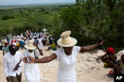 A woman stretches out her arms in prayer as she balances a stone on her head as a form of penance during a Good Friday ritual, in Ganthier, Haiti, April 14, 2017.