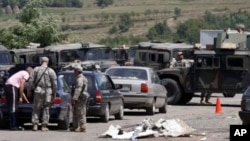 US soldiers serving in KFOR check vehicles from Serbia entering Kosovo after reopening a checkpoint, demolished and burned by angry Kosovo Serbs, in the village of Jarinje, on the Serbia-Kosovo border, July 28, 2011