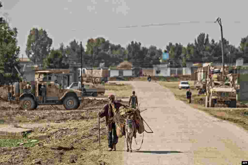 U.S. military armored vehicles patrol on the outskirts of Tal Tamr town along the M4 highway in the northeastern Syrian Hasakeh province, near the border with Turkey.