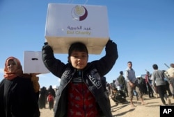 Iraqi citizens who fled the fighting between Islamic State militants and the Iraqi forces, carry boxes of aid supplies, at a camp for internally displaced people, in Khazer, east of Mosul, Iraq, Nov. 21, 2016.