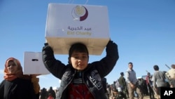 이라크 정부군과 수니파 무장조직 ISIL의 교전을 피해 달아난 주민들이 21일 모술 동부의 임시 대피소에서 구호품 상자를 들고 있다.