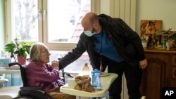 Marguerite Mouille, left, is greeted by her grandson Thierry Mouille at a nursing home in Kaysesberg, eastern France, Monday Dec. 21, 2020. (AP Photo/Jean-Francois Badias)