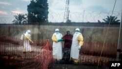 Un patient atteint d'Ebola est conduit par deux travailleurs médicaux dans une unité de soins d'urgence Biosecure (CUBE), à Beni, le 15 août 2018.