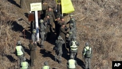 North Korean army soldiers are greeted by South Korean army soldiers, wearing helmets, as they cross the Military Demarcation Line inside the Demilitarized Zone (DMZ) to inspect the dismantled South Korean guard post in Cheorwon, Dec. 12, 2018. 