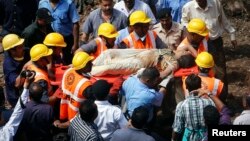 Rescue workers use a stretcher to carry a woman who was rescued from the rubble at the site of a collapsed residential building in Mumbai, Sept. 27, 2013