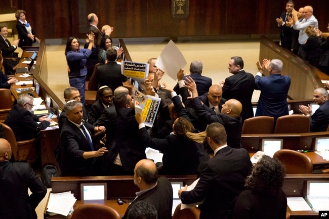 Israeli Arab members hold signs in protest as security pushes them out as U.S. Vice President Mike Pence speaks in Israel's parliament in Jerusalem, Monday, Jan. 22, 2018.