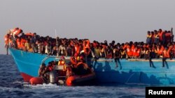 A rescue boat of the Spanish NGO Proactiva approaches an overcrowded wooden vessel with migrants from Eritrea, off the Libyan coast in Mediterranean Sea, August 29, 2016.