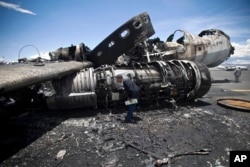 An airport official looks at the wreckage of a military transport aircraft destroyed by Saudi-led airstrikes, at the Sanaa International airport, in Yemen, May 5, 2015.