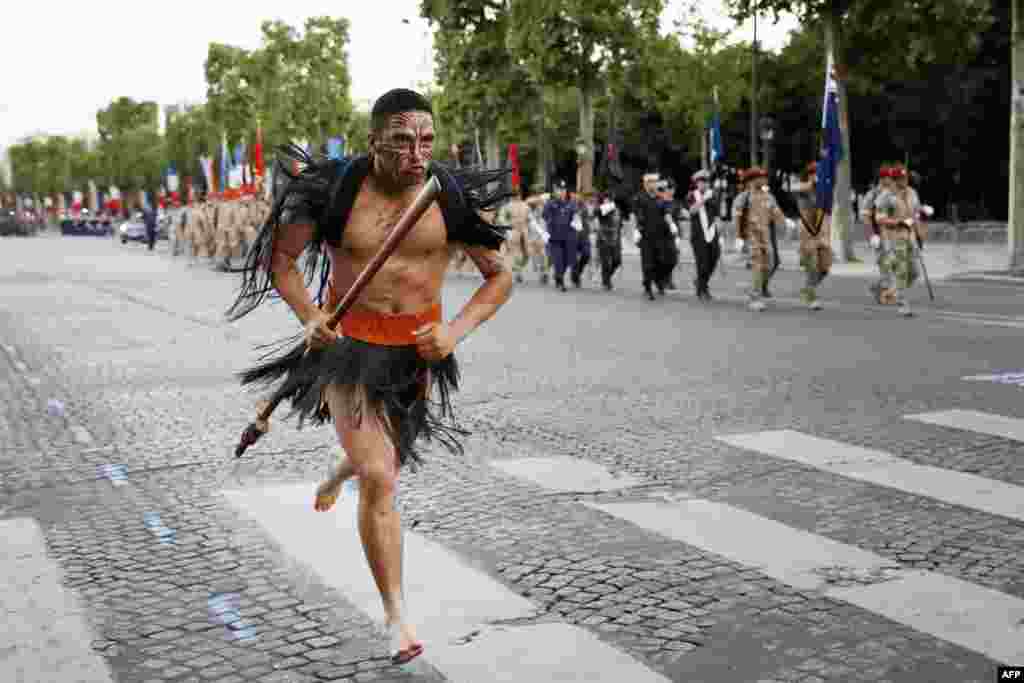 파리에서 프랑스 혁명기념일 행군을 준비하는 뉴질랜드 병사들 앞으로 마우리족 전사가 달려가고 있다. &nbsp;