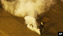 A protester runs to throw back a tear gas canister fired by riot police during clashes following a rally by opponents of Prespa Agreement, outside the Greek Parliament in Athens, Jan. 24, 2019. 