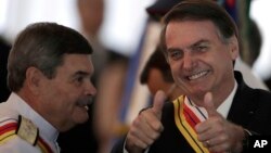Brazil's President Jair Bolsonaro flashes two thumbs up standing next to Adm. Marcus Vinicius Oliveira dos Santos, Supreme Military Court president, who presented Bolsonaro with the Order of Military Judicial Merit, in Brasilia, Brazil, March 28, 2019.
