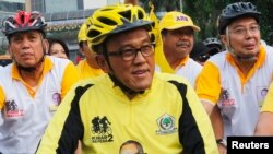 FILE - Aburizal Bakrie cycling with his party members in Jakarta, Oct. 21, 2012. 