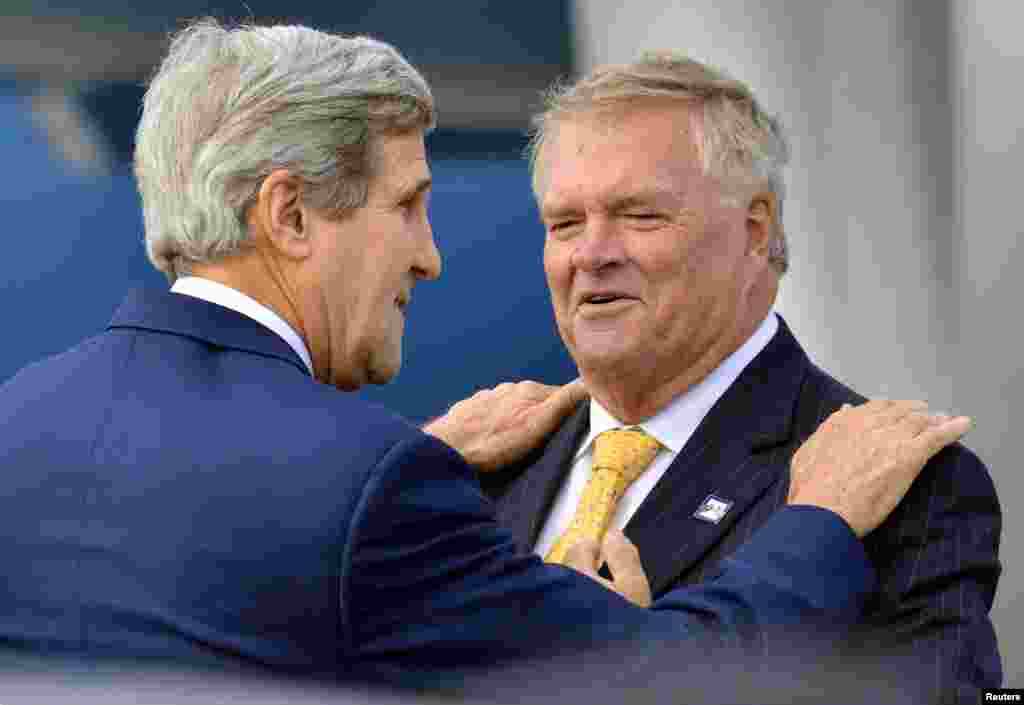 U.S. Secretary of State John Kerry rests his hands on the shoulders of Australian Ambassador to the U.S., Kim Beazley, upon his arrival in Sydney, Aug. 11, 2014.