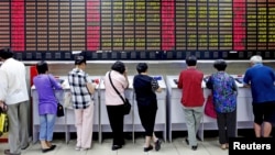 Investors look at computer screens showing stock information at a brokerage house in Shanghai, China, July 8, 2015.