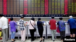 Investors look at computer screens showing stock information at a brokerage house in Shanghai, China, July 8, 2015.