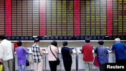 FILE - Investors look at computer screens showing stock information at a brokerage house in Shanghai, China, July 8, 2015.