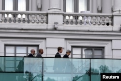 U.S. Secretary of State John Kerry, right, walks using crutches at the garden of the hotel where the Iran nuclear talks meetings are being held in Vienna, Austria July 9, 2015.