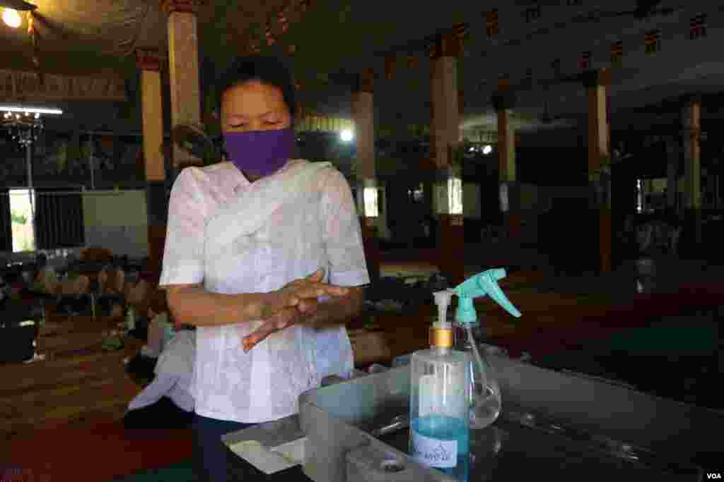 ស្រ្តីម្នាក់កំពុងលាងដៃនឹងអាល់កុល អំឡុងពេលប្រារព្ធពិធីបុណ្យចូលឆ្នាំខ្មែរថ្ងៃទី២ នៅវត្តថាន់ រាជធានីភ្នំពេញ នៅថ្ងៃទី១៤ ខែមេសា ឆ្នាំ២០២០។ (កាន់ វិច្ឆិកា/VOA)
