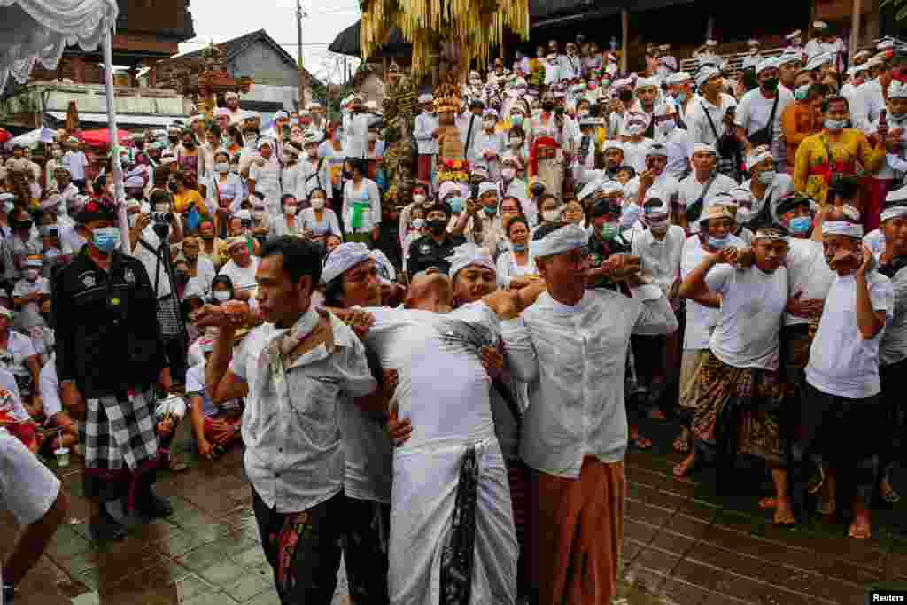 Balinese Hindu men are seen in a trance during the sacred Ngerebong ritual in Bali, Indonesia.