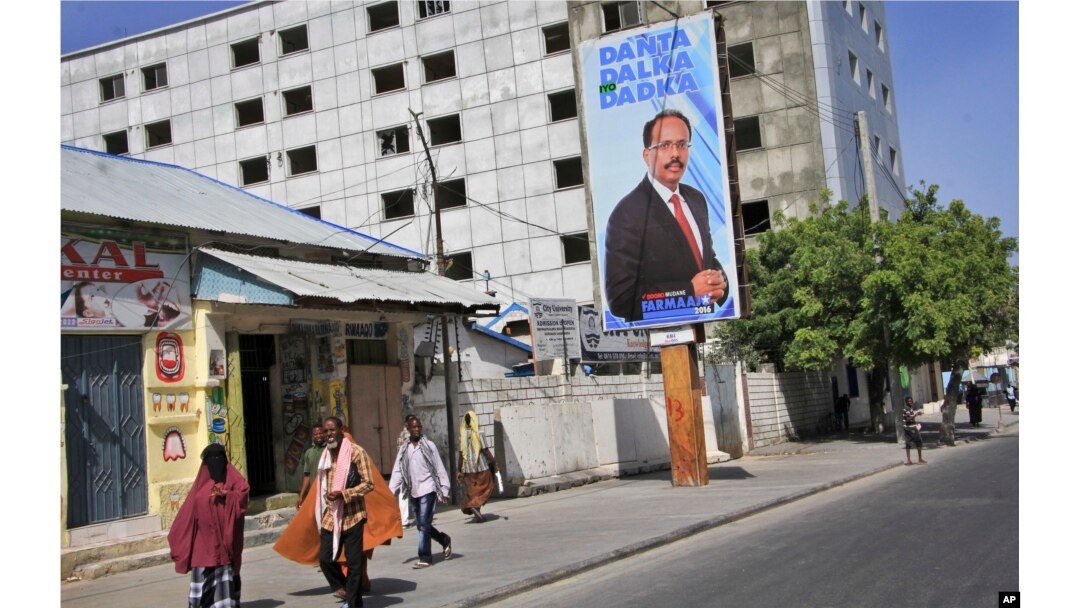 Somalis walk past a campaign poster for candidate Mohamed Abdullahi Farmaajo on the eve of presidential elections in Mogadishu, Somalia, Feb. 7, 2017. Graft - vote-buying, fraud, intimidation - is the top concern in a nation that Transparency International now rates as the most corrupt in the world.