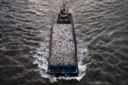 Sebuah kapal mengangkut limbah yang dapat didaur ulang melewati East River dekat Manhattan, New York 24 Juni 2013. (REUTERS / Zoran Milich)