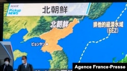 Pejalan kaki berjalan melewati layar yang menampilkan peta Korea Utara menembakkan sesuatu seperti rudal balistik ke laut lepas pantai timurnya menurut Korea Selatan dan Jepang, 5 Januari 2022. (Foto: AFP)