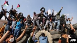 Les manifestants palestiniens brandissent des drapeaux à l’arrière d’un camion à la frontière entre Israël et Gaza, le 27 avril 2018