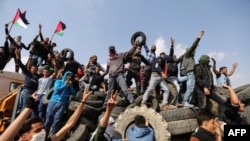 Les manifestants palestiniens brandissent leur drapeau national à l’arrière d’un camion à la frontière entre Israël et Gaza, le vendredi 27 avril 2018