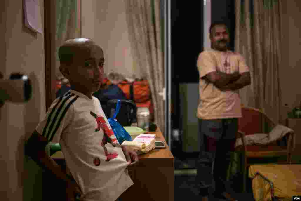 Syed Nadim Rizwi is seen in his room with one of his sons. A Shia Muslim, he fled Pakistan after a number of relatives were murdered. (J. Owens/VOA)