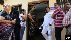 An Indian paramilitary soldier stands guard as voters wait at a polling station in Bangalore, India, May 12, 2018. India's southern state of Karnataka headed to the polls to elect 224 lawmakers.