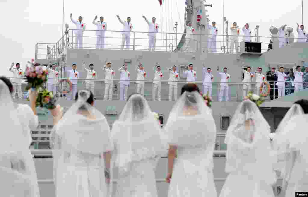 Navy personnel of People's Liberation Army (PLA) wave at their brides during a mass wedding at a military base in Zhoushan, Zhejiang province, China.